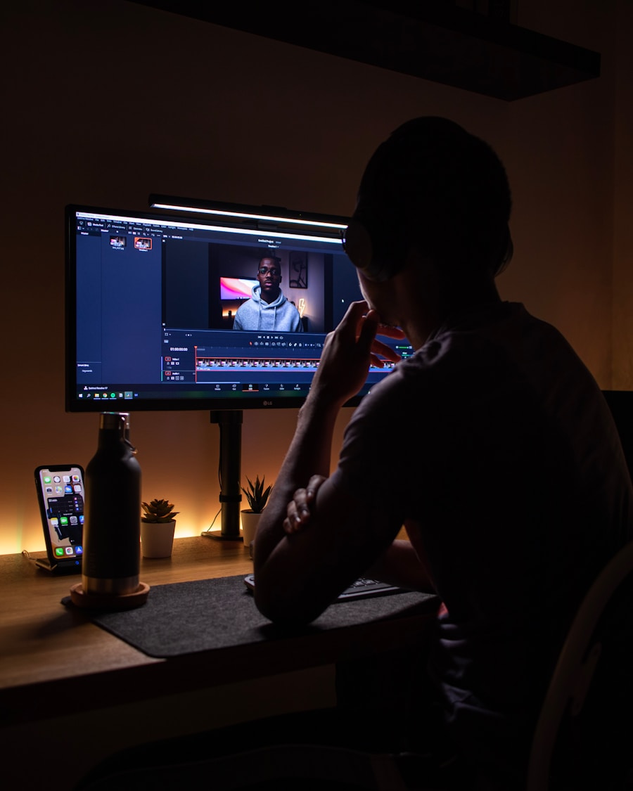 Una persona editando video frente a una pantalla en una habitación a oscuras