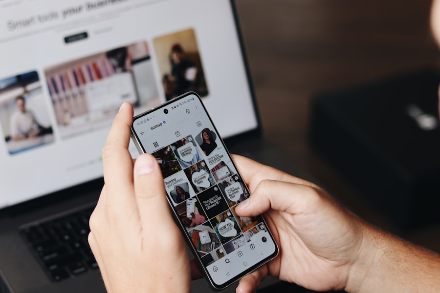 Alguien mirando redes sociales en el teléfono con una computadora de fondo